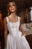 Woman wearing a white dress with lace details and multiple necklaces indoors.